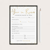 A 'Year in Review' fill-in worksheet template for 2026, featuring a black and gold design, shown flat-lay style next to a white pencil on a light beige background.