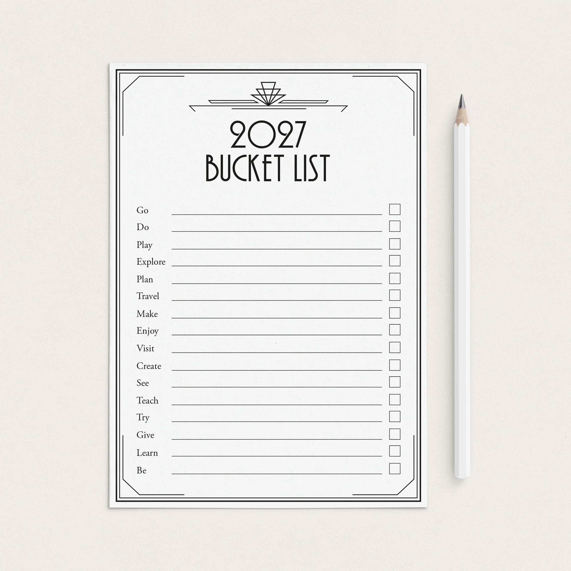 A 2027 bucket list printable sheet with black text and checkboxes on a white background, styled flat-lay next to a white pencil on a light beige surface.