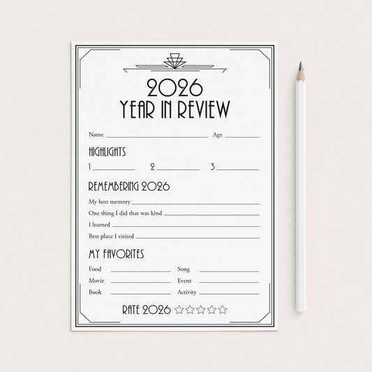 A 2026 Year in Review reflection worksheet with black text and lines on a white sheet, displayed on a light beige background next to a white pencil.