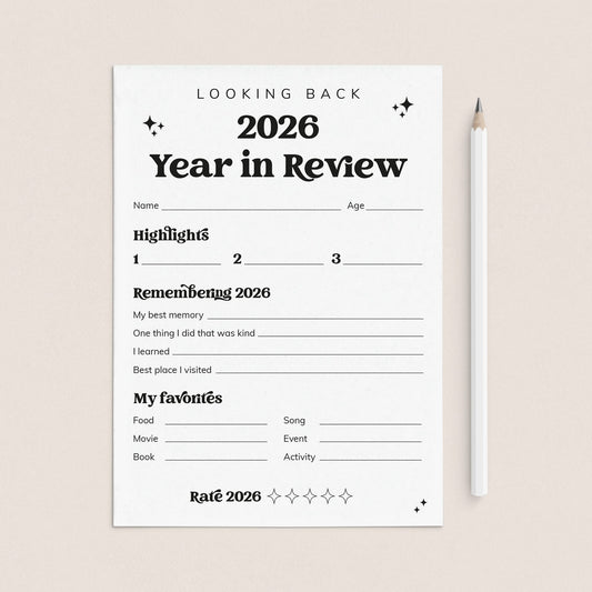 A white '2026 Year in Review' reflection sheet with black text and lines, placed on a light beige background next to a white pencil.