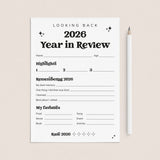 A white '2026 Year in Review' reflection sheet with black text and lines, placed on a light beige background next to a white pencil.