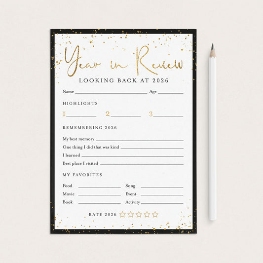 A 'Year in Review' fill-in worksheet template for 2026, featuring a black and gold design, shown flat-lay style next to a white pencil on a light beige background.