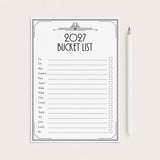 A 2027 bucket list printable sheet with black text and checkboxes on a white background, styled flat-lay next to a white pencil on a light beige surface.
