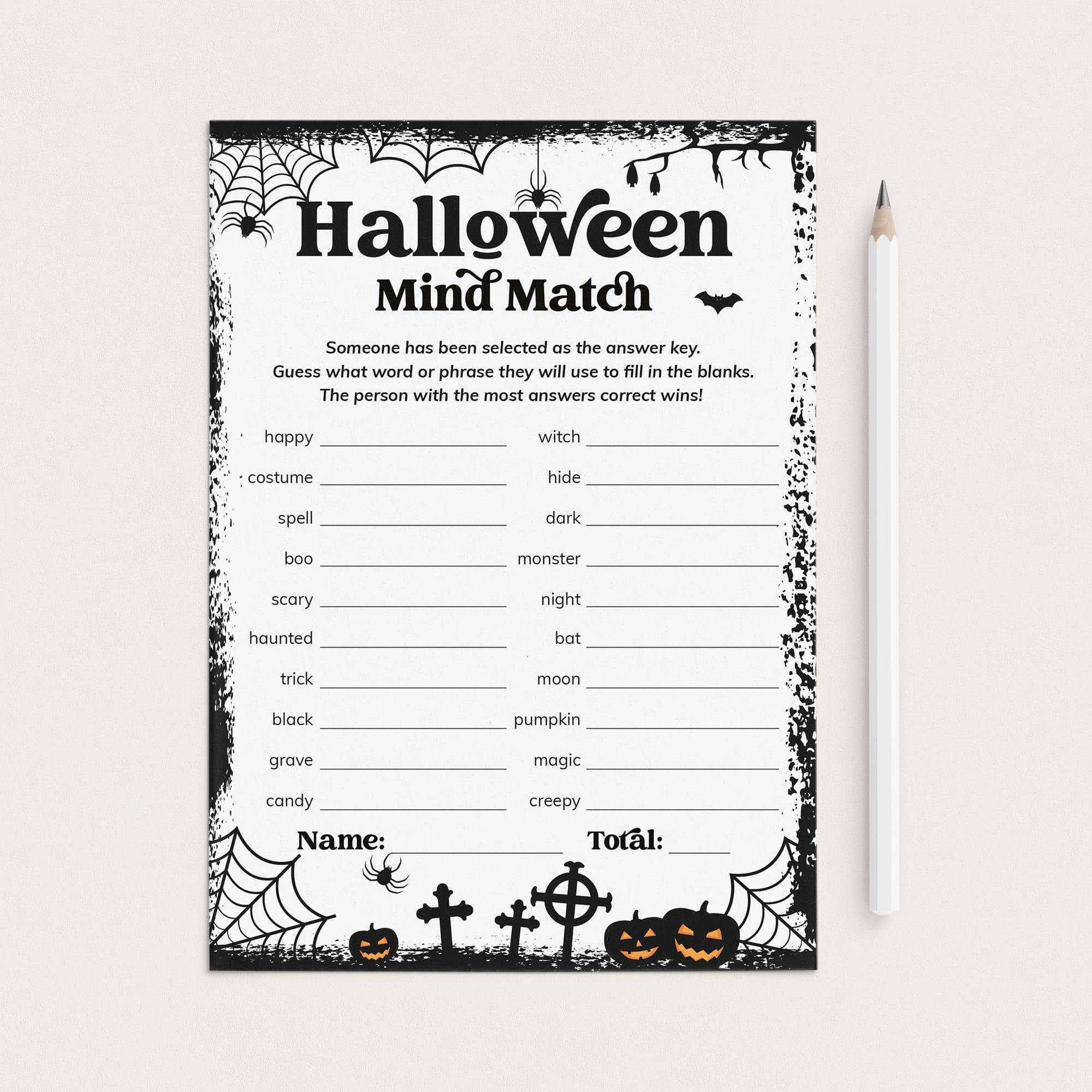 A printable Halloween-themed worksheet card titled 'Halloween Mind Match' with black spiderwebs, bats, pumpkins, and fill-in lines on a white background, shown next to a white pencil on a light neutral surface.